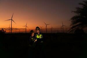 Engineers working on wind turbines farm at sunset, Wind turbines are alternative energy source. photo