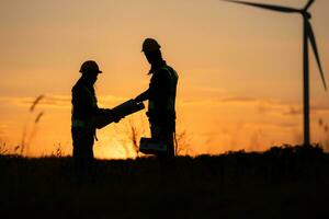 Silhouette of Engineer in charge of wind energy against a background of wind turbines. photo