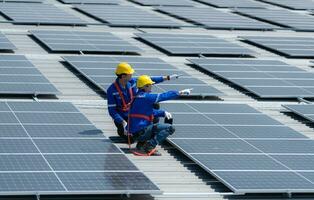 Both of technicians is installing solar panels on the roof of the warehouse to change solar energy into electrical energy for use in factories. photo