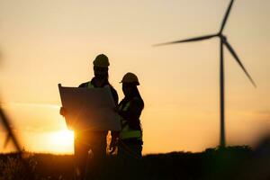 Silhouette of Engineer in charge of wind energy against a background of wind turbines. photo