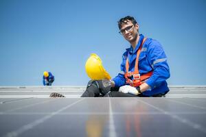 Technician repairing solar panels take off his hat and rest in the scorching sun on a factory roof covered with solar panels to receive solar energy. photo