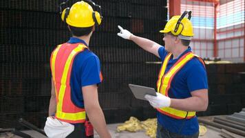 almacén trabajadores en difícil sombreros y cascos, inspeccionar y contar acero en el depósito. foto