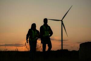 Silhouette of Engineer in charge of wind energy against a background of wind turbines. photo