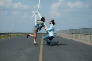 On the road, a young couple proposes to each other, with wind turbines in the background. photo