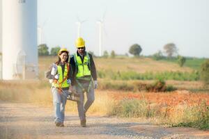 Engineer and worker discussing on a wind turbine farm with blueprints photo