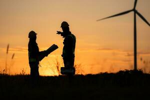 Silhouette of Engineer in charge of wind energy against a background of wind turbines. photo