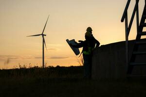 Silhouette of Engineer in charge of wind energy against a background of wind turbines. photo
