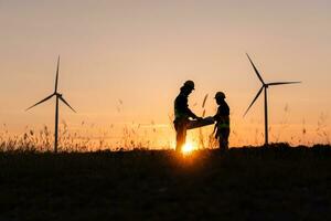 Silhouette of Engineer in charge of wind energy against a background of wind turbines. photo