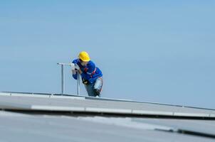 un nuevo técnico aprendiz trabajando en solar paneles con un temor de alturas foto