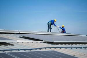 A young technician intern working on solar panels is fear of heights with senior engineers who are always helping out photo