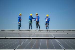 Group of engineers standing on solar panels with blue sky in the background photo