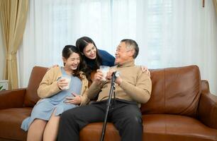 A happy family sits on the sofa in the living room, Father and daughter are pregnant drinking milk and talk to each other. photo