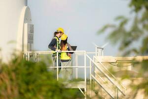 Engineer and worker discussing on a wind turbine farm with laptop photo