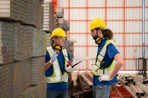 Warehouse workers in hard hats and helmets stand in the warehouse to count and inspect the steel in the warehouse. photo