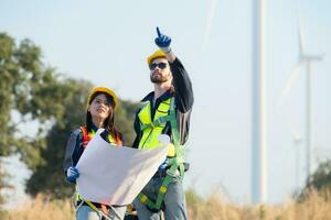 Engineer and worker discussing on a wind turbine farm with blueprints photo