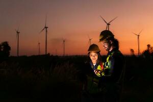 Engineers working on wind turbines farm at sunset, Wind turbines are alternative energy source. photo