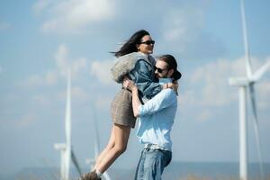 Back view of young couple walking on the road with wind turbines in background photo