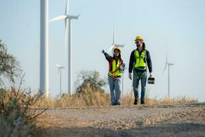 Engineer and worker discussing on a wind turbine farm with blueprints photo