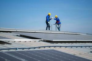 A young technician intern working on solar panels is fear of heights with senior engineers who are always helping out photo