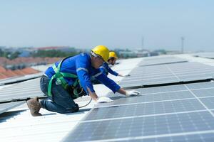 ambos de técnicos es instalando solar paneles en el techo de el almacén a cambio solar energía dentro eléctrico energía para utilizar en fábricas. foto