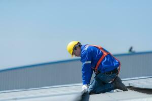 un técnico es instalando solar paneles en el techo de el almacén a cambio solar energía dentro eléctrico energía para utilizar en fábricas. foto