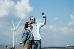 happy young couple taking selfie with smartphone in front of windmills photo