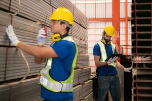 Warehouse workers in hard hats and helmets stand in the warehouse to count and inspect the steel in the warehouse. photo