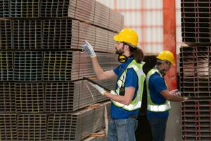 Warehouse workers in hard hats and helmets stand in the warehouse to count and inspect the steel in the warehouse. photo