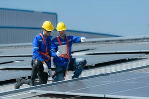 ambos de técnicos es instalando solar paneles en el techo de el almacén a cambio solar energía dentro eléctrico energía para utilizar en fábricas. foto