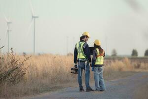 Engineer and worker discussing on a wind turbine farm with laptop photo