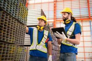 Warehouse workers in hard hats and helmets stand in the warehouse to count and inspect the steel in the warehouse. photo