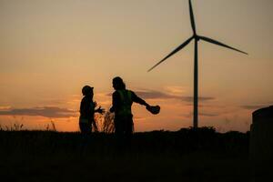 Silhouette of Engineer in charge of wind energy against a background of wind turbines. photo