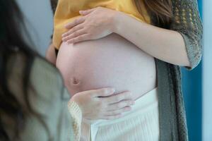 ambos de joven esperando madre participación bebé en embarazada barriga. maternidad prenatal cuidado y mujer el embarazo concepto. foto