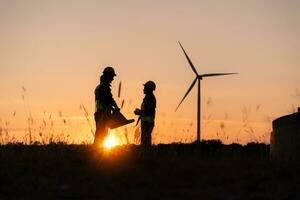 Silhouette of Engineer in charge of wind energy against a background of wind turbines. photo