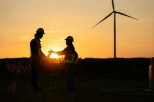 Silhouette of Engineer in charge of wind energy against a background of wind turbines. photo