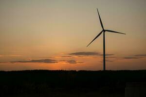 Wind turbines are a large source of natural energy that is turned into electrical energy and then used in everyday life. On sunset background photo