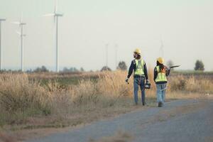 Engineer and worker discussing on a wind turbine farm with laptop photo