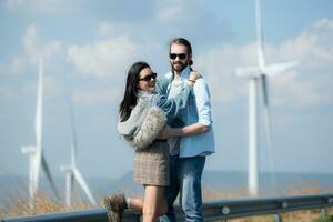 Back view of young couple walking on the road with wind turbines in background photo