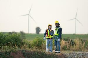 Engineer and worker discussing on a wind turbine farm with blueprints photo