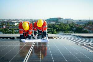 Engineer and technician working on the solar panel on the warehouse roof to inspect the solar panels that have been in operation for some time. photo