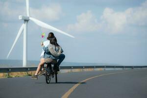 espalda ver de un joven mujer montando un bicicleta con su novio en el la carretera foto