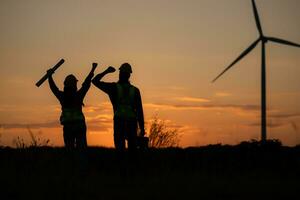 silueta de ingeniero en cargar de viento energía en contra un antecedentes de viento turbinas foto