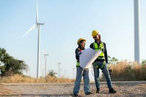 Engineer and worker discussing on a wind turbine farm with blueprints photo
