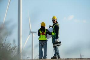 Engineer and worker discussing on a wind turbine farm with blueprints photo