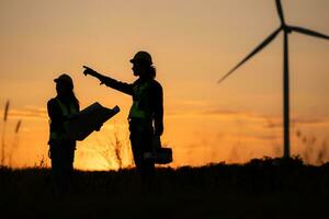 Silhouette of Engineer in charge of wind energy against a background of wind turbines. photo