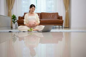 embarazada mujer come ensalada como un bocadillo mientras sentado en el piso de su hogar. foto