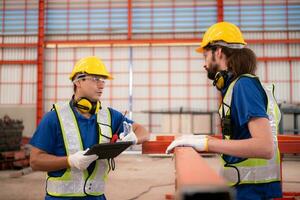 Portrait of two workers using digital tablet stand in front of the red steel structure photo