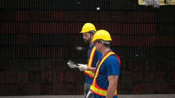 almacén trabajadores en difícil sombreros y cascos, inspeccionar y contar acero en el depósito. foto