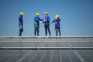 Group of engineers standing on solar panels with blue sky in the background photo