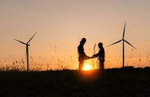 Silhouette of Engineer in charge of wind energy against a background of wind turbines. photo